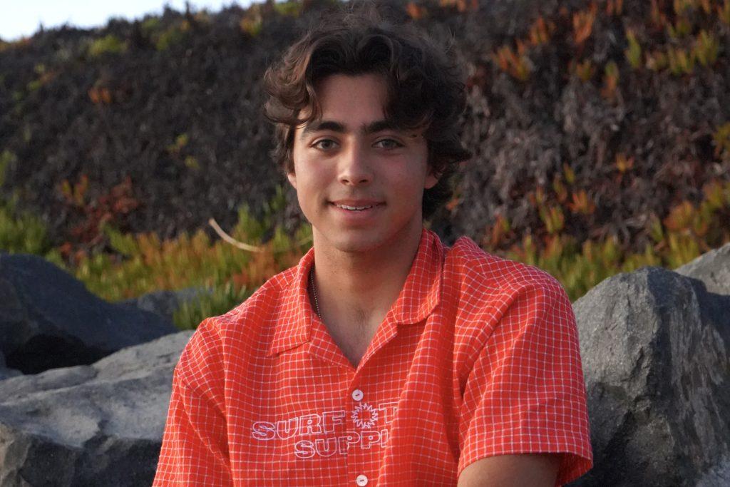 Larry Flores wore a red shirt from Surf Trip Supply at a beach in Malibu. Flores said each item is designed intentionally. Photos by Liam Zieg